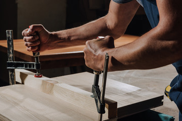 Obraz premium cropped shot of carpenter in apron working on wood at workshop