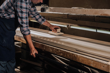 cropped shot of woodworker planing wood with hand plane at workshop