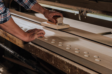 cropped shot of woodworker planing wood with hand plane at workshop