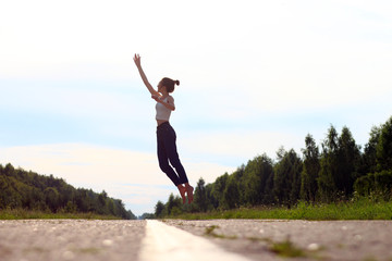 Fototapeta na wymiar Happy young woman jumping having Fun Outdoors on the road. concept of freedom.