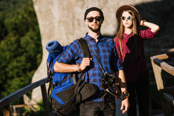 Fototapeta na wymiar A couple traveling by the mountains wearing hipster clothes with backpack, vintage camera and binoculars