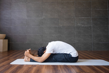 Experienced yogi doing seated forward bend yoga pose in gym. Man practicing yoga. Yogi concept....