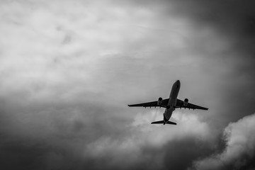 Commercial airplane on grey sky and clouds with copy space. Failed vacation. Hopeless and despair concept. Moody sky and transport plane. Sad emotional scene. Background of aircraft flight.
