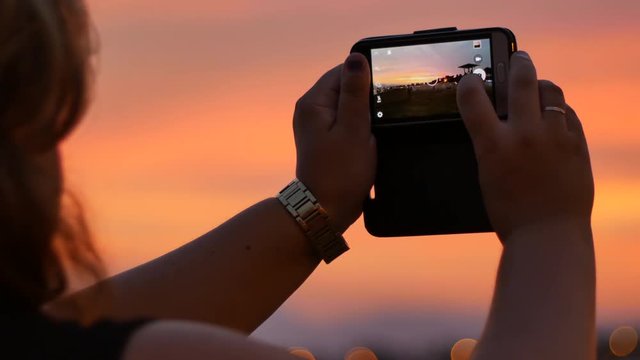 silhouette hand holding smartphone take photo at sunset and flare light