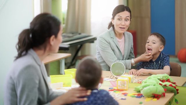 Cute boy and woman speech therapist are working together at therapy session
