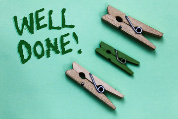 Text sign showing Well Done. Conceptual photo telling person that he made his task or job in perfect shape Three brown green vintage clothespins clear background Holding things.
