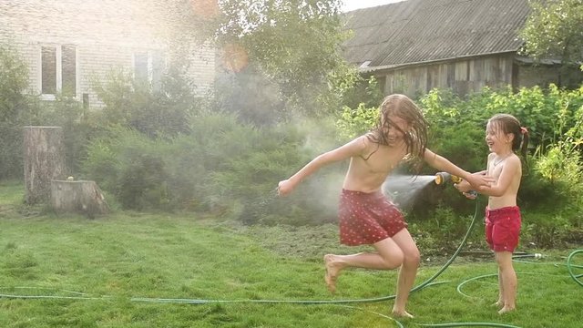 fun water game of two girls at garden in summer
