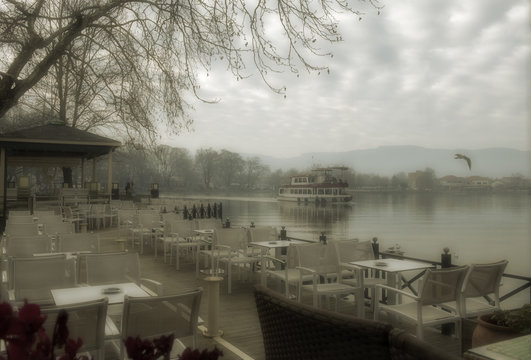 Foggy day on lake Pamvotis. A river barge ship trasfer people to small island into the lake. Ioannina city, Greece.Vintage look processed