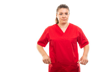 Fototapeta premium Young medical nurse wearing red scrub showing empty pockets gesture.