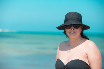 Portuguese woman with hat and black glasses with blue sea truquesa background.