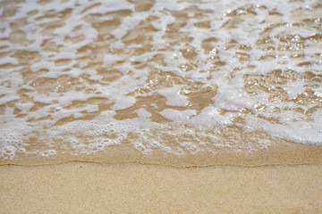 Fototapeta na wymiar Wave of ocean on sandy beach background.