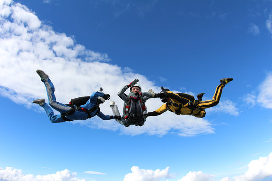 Skydiving. Two instructors are training a student to fly.