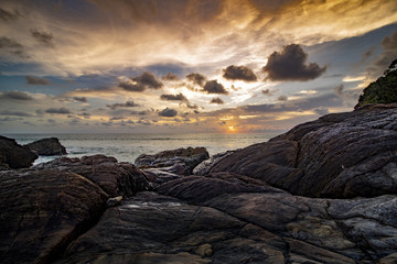 HDR processed dramatic sunset over sea beach on south islands in Thailand with a natural rock in the foreground.