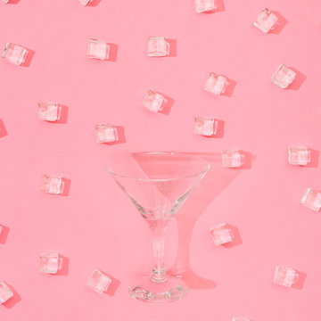 Ice cubes pattern with martini glass on pastel pink background. Minimal summer drink concept. Flat lay.