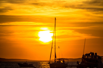 Sunset over sea with silhouettes of yachts