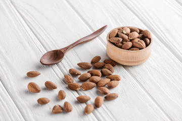 almonds with wooden bowl and spoon on white wooden table