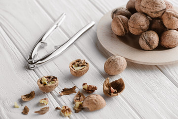 Fototapeta na wymiar brown walnuts with metal nutcracker on wooden tabletop