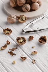 Fototapeta na wymiar walnuts with metal nutcracker on white wooden surface