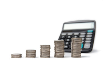 Coin stacks and calculator on a white background.