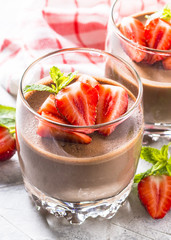 Chocolate dessert of whipped cream and strawberries in glass.