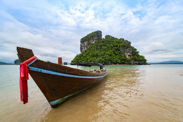 Boat on the beach and background rock island landscape in the southern tip of Thailand.