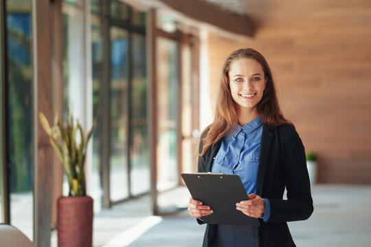 Happy Beautiful Business Woman With Clipboard In The Office.