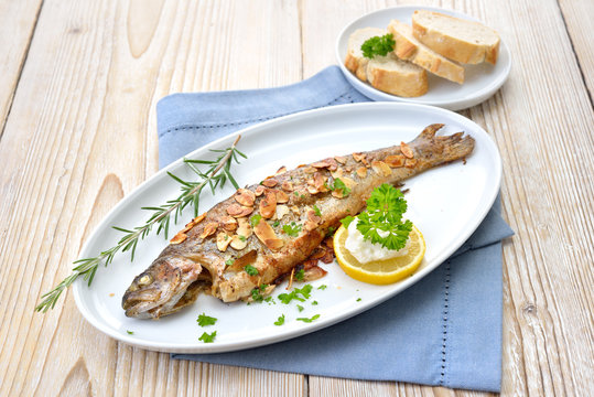 Gebratene Forelle M&uuml;llerin Art mit Butter-Mandeln, serviert mit Meerrettich, Zitrone und Baguette  &ndash; Fried trout with almonds, butter and creamed horseradish