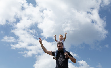 Fototapeta na wymiar Father holding little girl on his shoulder while on top of the mountain. Sunny summer day. Freedom and parenting