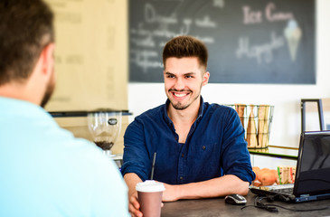 Barista gives cup to client visitor. Man receive drink at bar counter. Cappuccino or cacao with straw. Served in paper cup coffee to go. Guy barista at bar serve coffee for client. Enjoy your drink