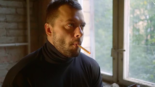 young man smokes a cigarette in a ruined room close-up. the smoke of the fire light. boy smokes. lips men. addiction smoker tobacco poison