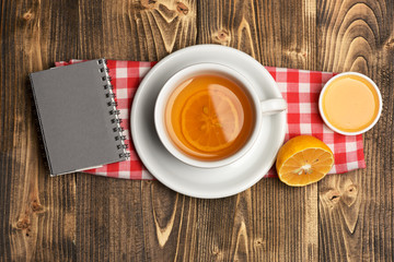 Tea cup with honey and little notebook, top view.