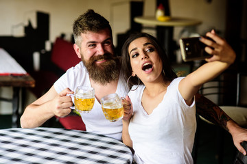 Couple cheerful mood drinking beer in pub. Couple in love on date drinks beer. Take selfie photo to...