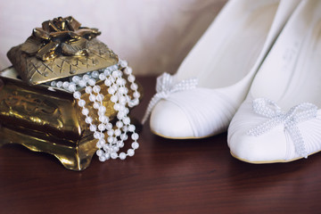 Jewellery box with white necklace and bridal shoes on background. Wedding morning. 