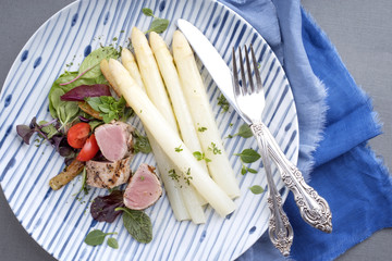 Modern style sliced pork fillet steak with white asparagus salad and roast potatoes as top view on a plate