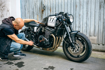 Biker checking custom motorcycle in front of the garage door