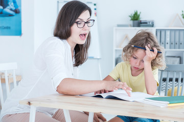 Speech therapist teaching a language an autistic child in an office