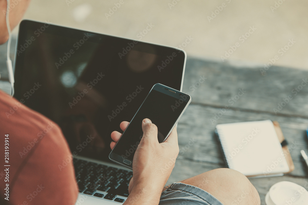 Wall mural man using internet on smart phone and laptop