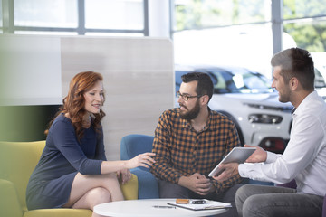 Professional car dealer offering luxurious vehicles during meeting with buyers in salon
