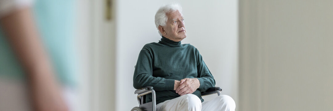 Panorama of disabled elderly man in the wheelchair in a nursing house