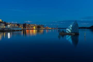 Exterior night view of the city and the glass structure art in the middle of the bay, located in Oslo