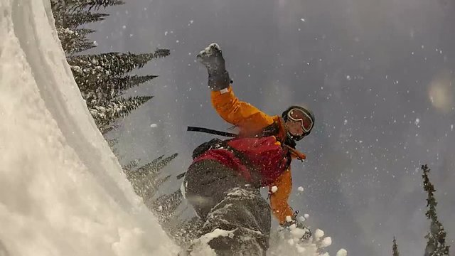 Snowboarder riding on forest slope with spray of snow, view from board