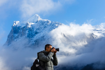 Nature photographer tourist with camera shoots while standing of the mountain.