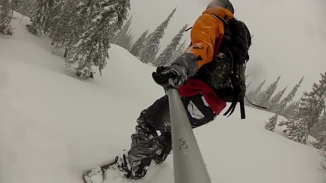 Snowboarder girl downhill at winter forest, view from behind