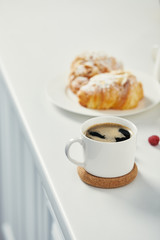 close up view of cup of aromatic coffee and croissants for breakfast on white surface