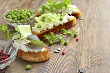 Crostini with cream cheese, green vegetables and herbs, copy space