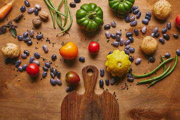Beans and raw vegetables with cutting board on wooden table