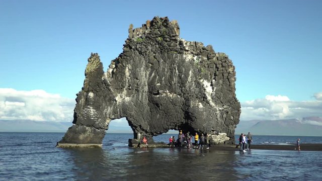 Families visiting the Hvitserkur sea stack rock arch in Northern Iceland, sunny day.mov