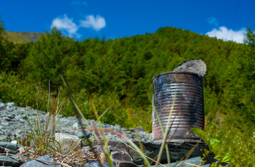 discarded can of canned food on the background of the mountain landscape