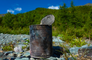 discarded can of canned food on the background of the mountain landscape