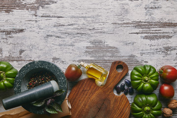 Vegetables and condiments in mortar on rustic wooden table